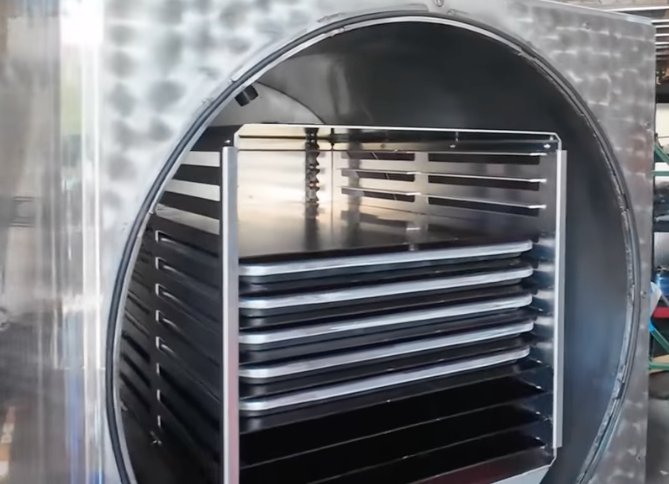 Interior chamber of a commercial freeze dryer showing the multi-tray rack